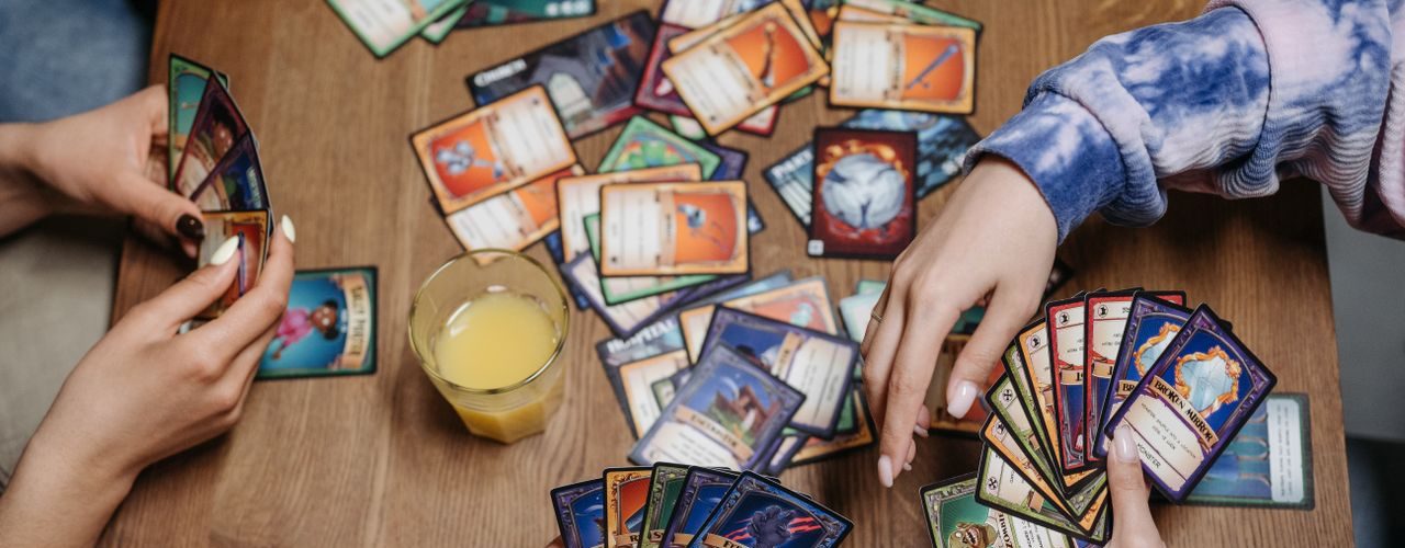 Close-up of friends playing a card game at a table, fostering socialization and togetherness.